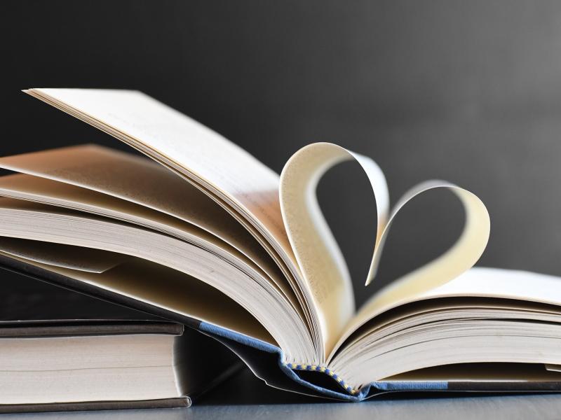 En bog ligger opslået på et bord; de to midterste sider er formet til et hjerte.