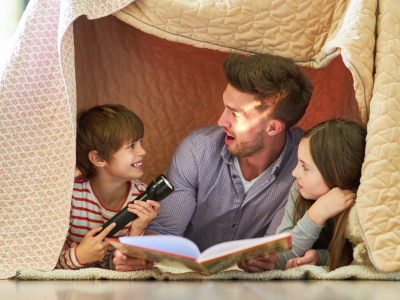 Mand læser højt for to børn i en hule